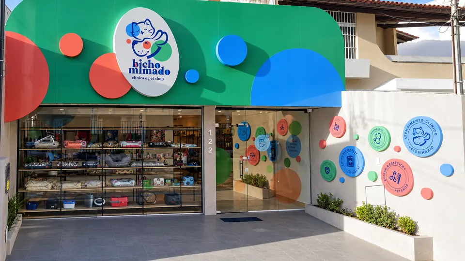 Fachada de Bicho Mimado: toldo verde con círculos de colores y el letrero ovalado con el logo, imagen tratada a partir de la fachada real