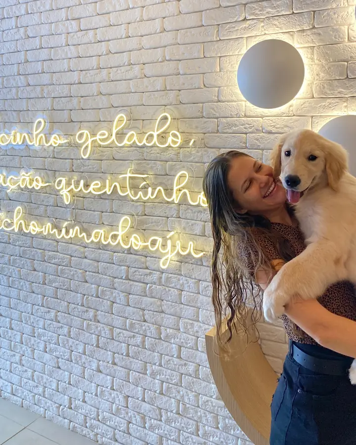 Cachorro golden en brazos, frente al neón de la recepción